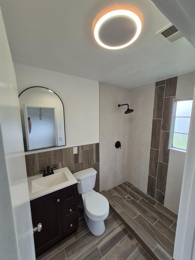 27261 Stanford Ave, Madera, CA 93637 - full bathroom with tile walls, tiled shower, vanity, wood tiled floors, and a wainscoted wall