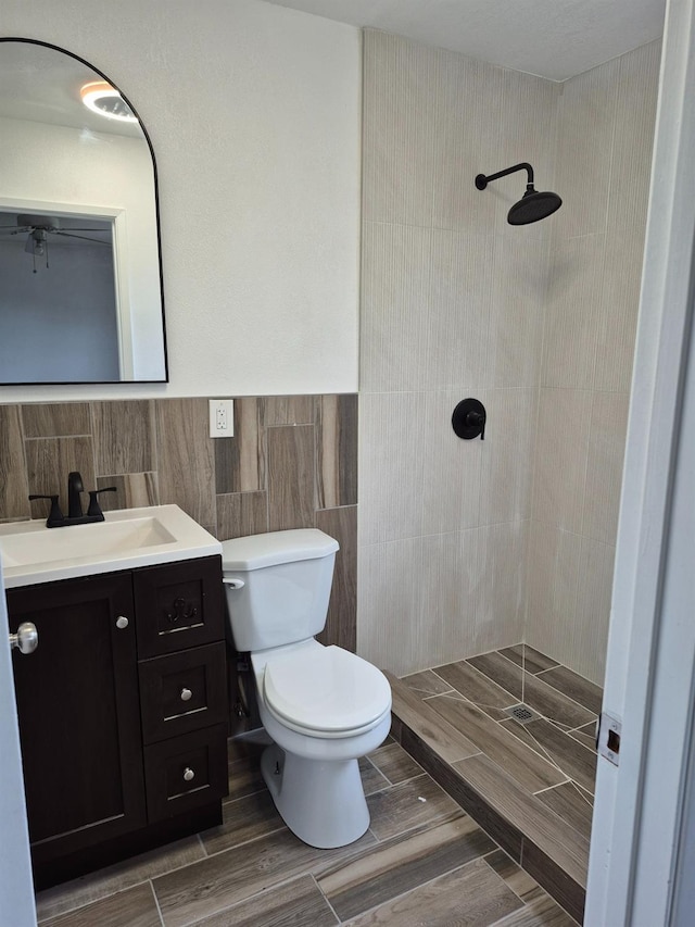 27261 Stanford Ave, Madera, CA 93637 - bathroom with toilet, wood finish floors, tile walls, vanity, and tiled shower