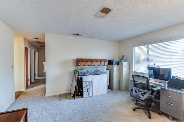 home office with a textured ceiling, light colored carpet, visible vents, and baseboards