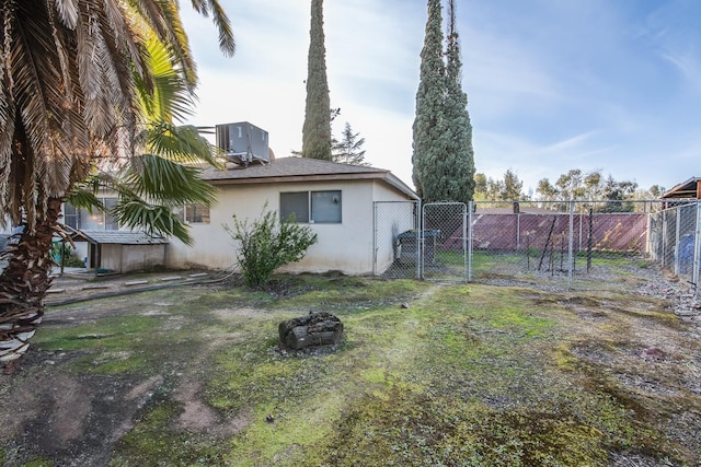 view of yard with fence, central AC unit, and a gate