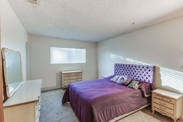 bedroom with visible vents, light colored carpet, and a textured ceiling
