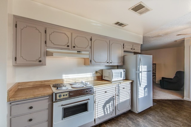 kitchen featuring visible vents, under cabinet range hood, dark wood finished floors, light countertops, and white appliances