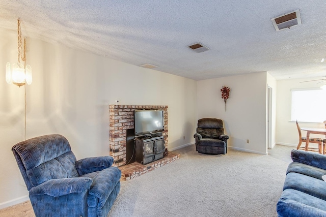 carpeted living room featuring visible vents, baseboards, a textured ceiling, and a wood stove