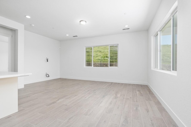 empty room with baseboards, visible vents, light wood finished floors, and recessed lighting
