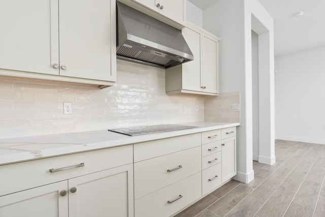 kitchen featuring black electric stovetop, light wood finished floors, backsplash, baseboards, and range hood