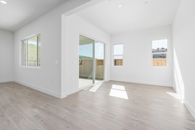 unfurnished room with baseboards, light wood-style floors, and recessed lighting