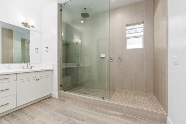 bathroom with vanity, wood finish floors, and a shower stall