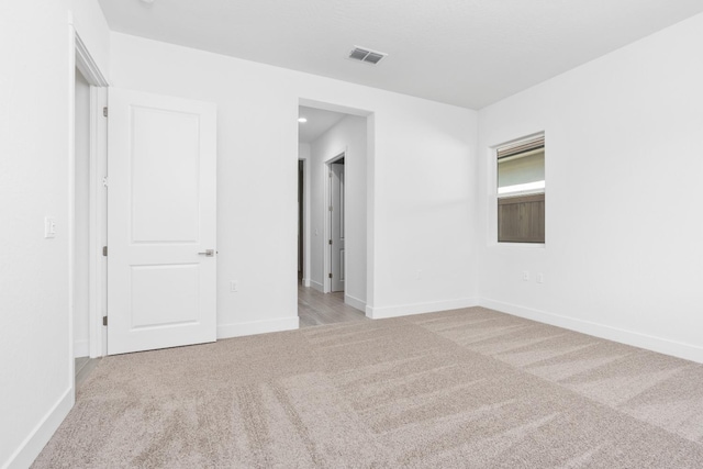 unfurnished room featuring baseboards, visible vents, and light colored carpet