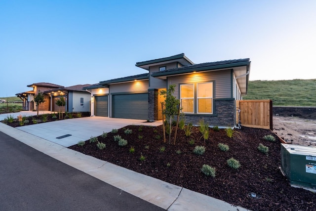 view of front of home featuring stone siding, concrete driveway, and a garage