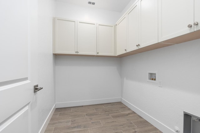 clothes washing area with baseboards, cabinet space, light wood-style floors, and visible vents