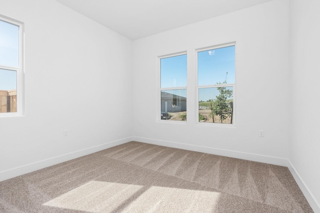 unfurnished room featuring carpet floors, baseboards, and a wealth of natural light
