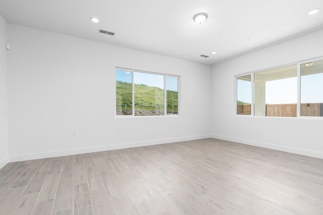 empty room with baseboards, light wood-style flooring, visible vents, and recessed lighting