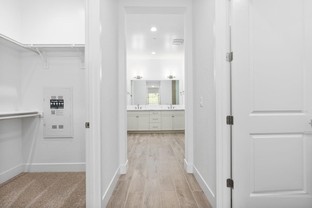 corridor featuring baseboards, a sink, and light wood-type flooring