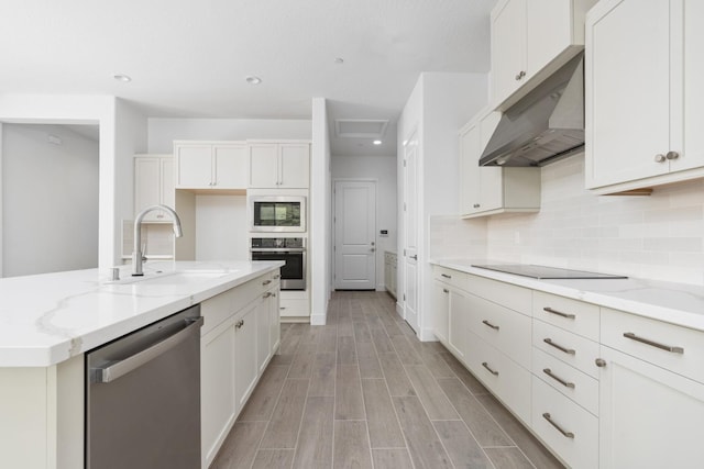 kitchen featuring tasteful backsplash, a sink, stainless steel appliances, under cabinet range hood, and light stone countertops