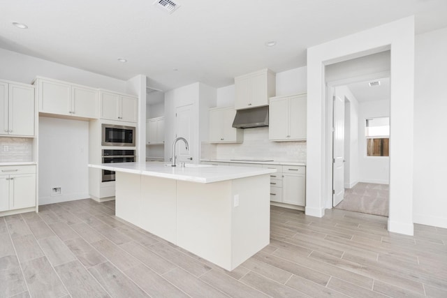 kitchen featuring black electric cooktop, oven, built in microwave, light countertops, and under cabinet range hood