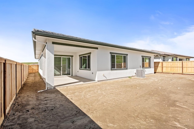 rear view of house with central air condition unit, a patio area, a fenced backyard, and stucco siding