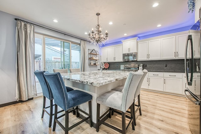dining space with recessed lighting, a notable chandelier, and light wood-type flooring