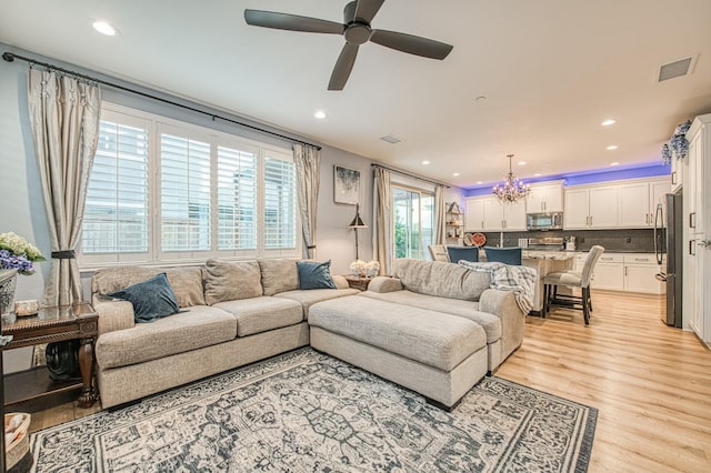 living area featuring light wood finished floors, visible vents, ceiling fan with notable chandelier, and recessed lighting