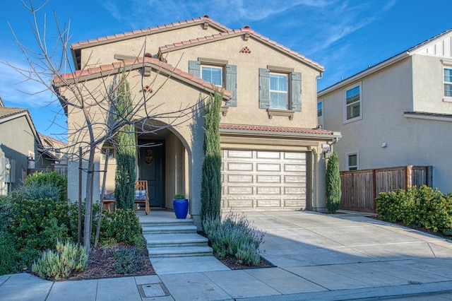 mediterranean / spanish house featuring a garage, a tiled roof, stucco siding, fence, and driveway