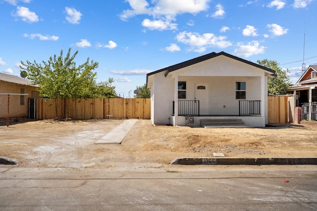 bungalow-style home featuring stucco siding, covered porch, and fence