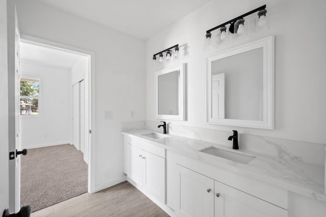 bathroom with a sink, baseboards, and double vanity