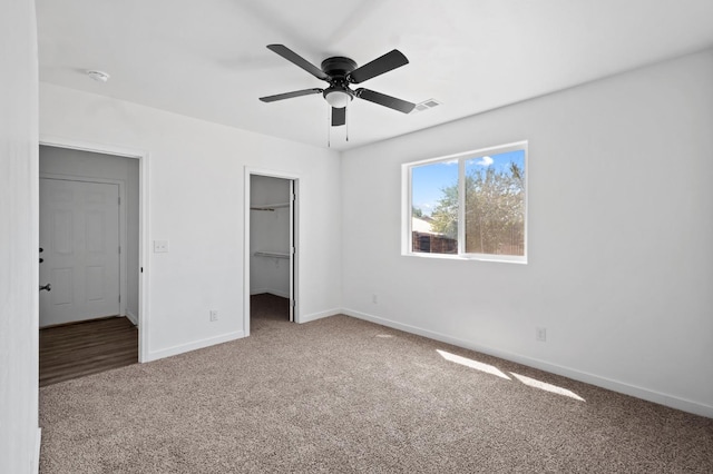 unfurnished bedroom featuring visible vents, a ceiling fan, carpet flooring, baseboards, and a spacious closet