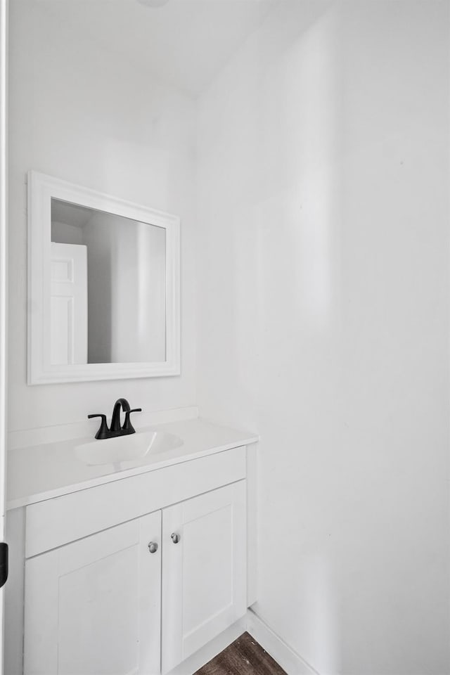 bathroom featuring baseboards, wood finished floors, and vanity