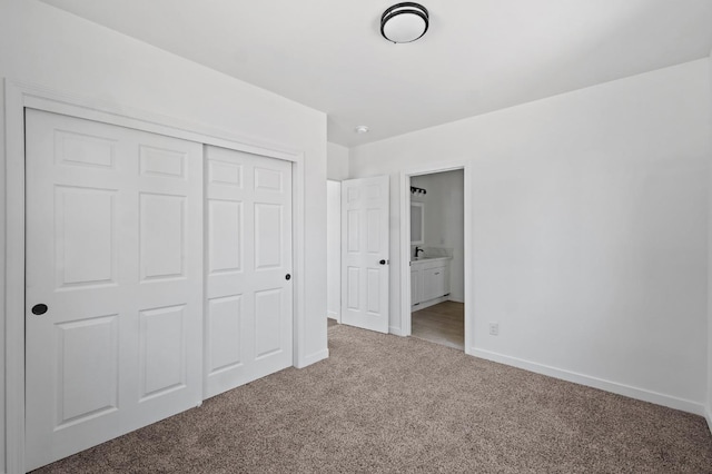 unfurnished bedroom featuring a closet, carpet flooring, ensuite bath, and baseboards