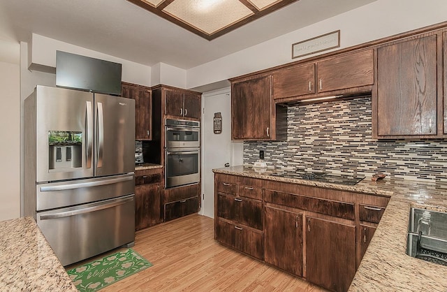 41371 Butte Way, Madera, CA 93636 - kitchen featuring appliances with stainless steel finishes, decorative backsplash, dark brown cabinets, light wood-style flooring, and light stone counters