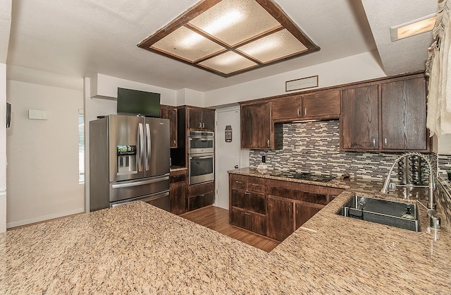 41371 Butte Way, Madera, CA 93636 - kitchen featuring stainless steel appliances, dark brown cabinetry, backsplash, light stone counters, and dark wood finished floors