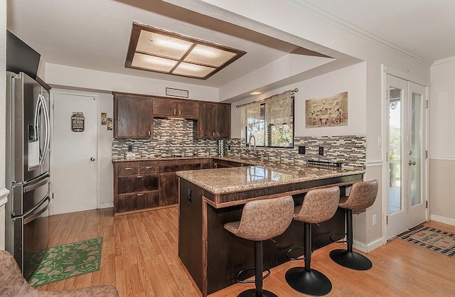 41371 Butte Way, Madera, CA 93636 - kitchen with stainless steel refrigerator with ice dispenser, dark brown cabinetry, a peninsula, light wood-type flooring, and tasteful backsplash