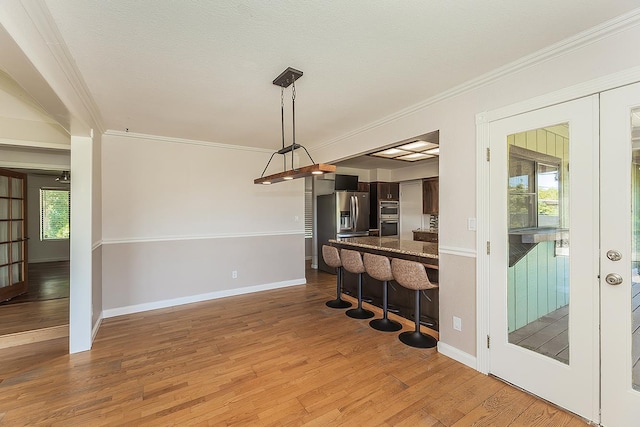 41371 Butte Way, Madera, CA 93636 - kitchen featuring a breakfast bar area, crown molding, wood finished floors, appliances with stainless steel finishes, and a peninsula