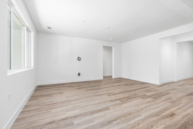 spare room featuring baseboards, visible vents, and light wood-style floors