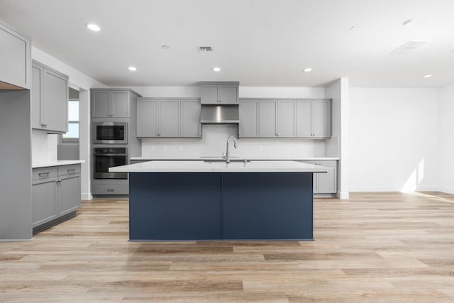 kitchen featuring tasteful backsplash, gray cabinetry, stainless steel appliances, and a sink