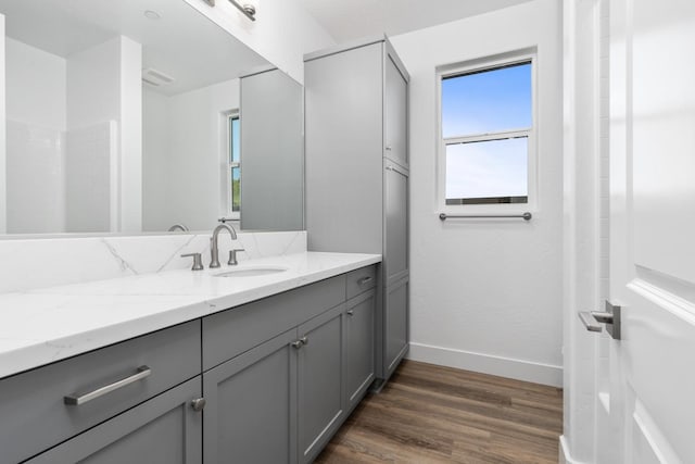 bathroom featuring visible vents, baseboards, wood finished floors, and vanity