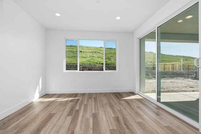 empty room with recessed lighting, wood finished floors, and baseboards