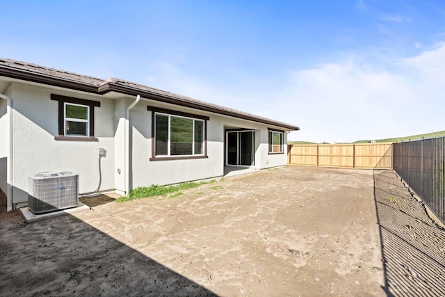 back of house with central AC, a fenced backyard, and stucco siding