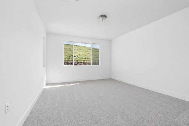 carpeted spare room featuring baseboards