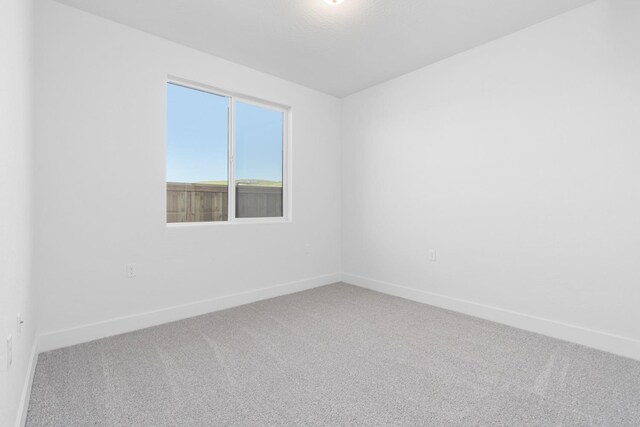 unfurnished room with baseboards and carpet flooring