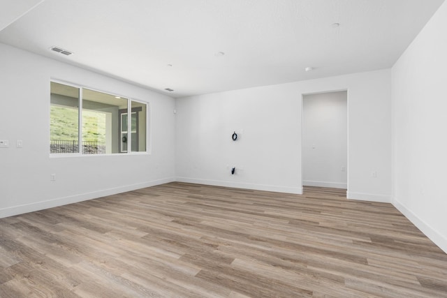unfurnished room featuring light wood-type flooring, baseboards, and visible vents