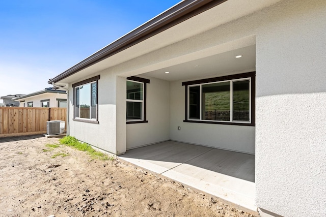 exterior space with fence, central AC unit, stucco siding, and a patio