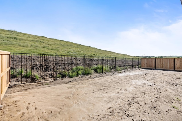view of yard with fence and a rural view