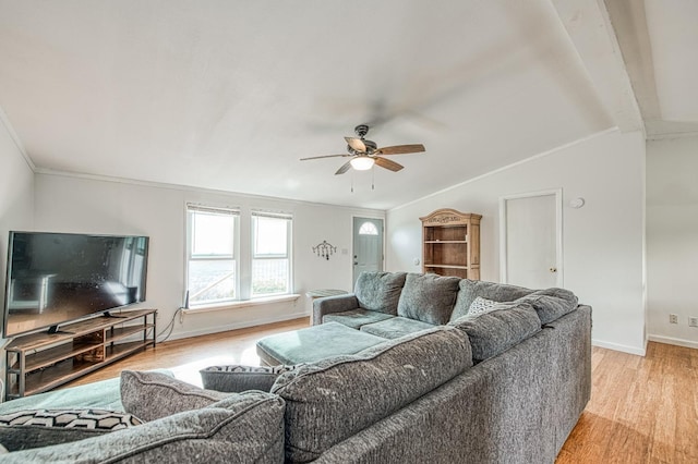 living room featuring ornamental molding, a ceiling fan, light wood finished floors, baseboards, and vaulted ceiling