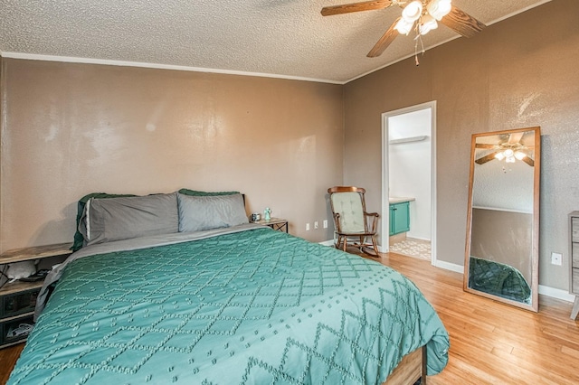 bedroom with a ceiling fan, wood finished floors, baseboards, ornamental molding, and a textured ceiling