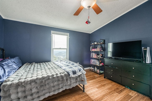 bedroom featuring lofted ceiling, ornamental molding, wood finished floors, a textured ceiling, and a ceiling fan