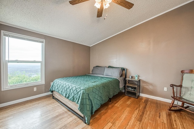 bedroom featuring a textured ceiling, wood finished floors, and vaulted ceiling