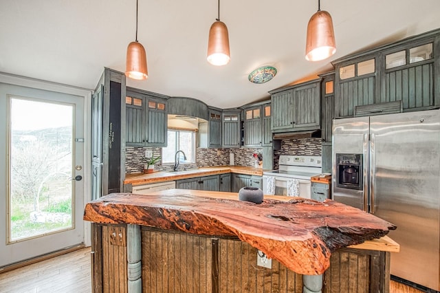 kitchen with electric range, under cabinet range hood, tasteful backsplash, stainless steel fridge, and light countertops