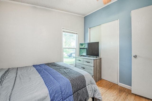 bedroom with light wood-type flooring, a textured ceiling, a closet, and crown molding