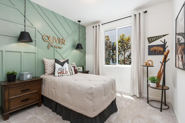 bedroom with light carpet, a decorative wall, and baseboards