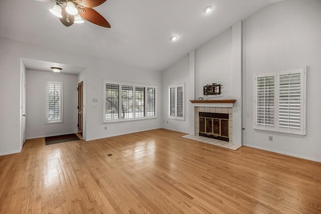 unfurnished living room with a ceiling fan, high vaulted ceiling, a fireplace, wood finished floors, and baseboards